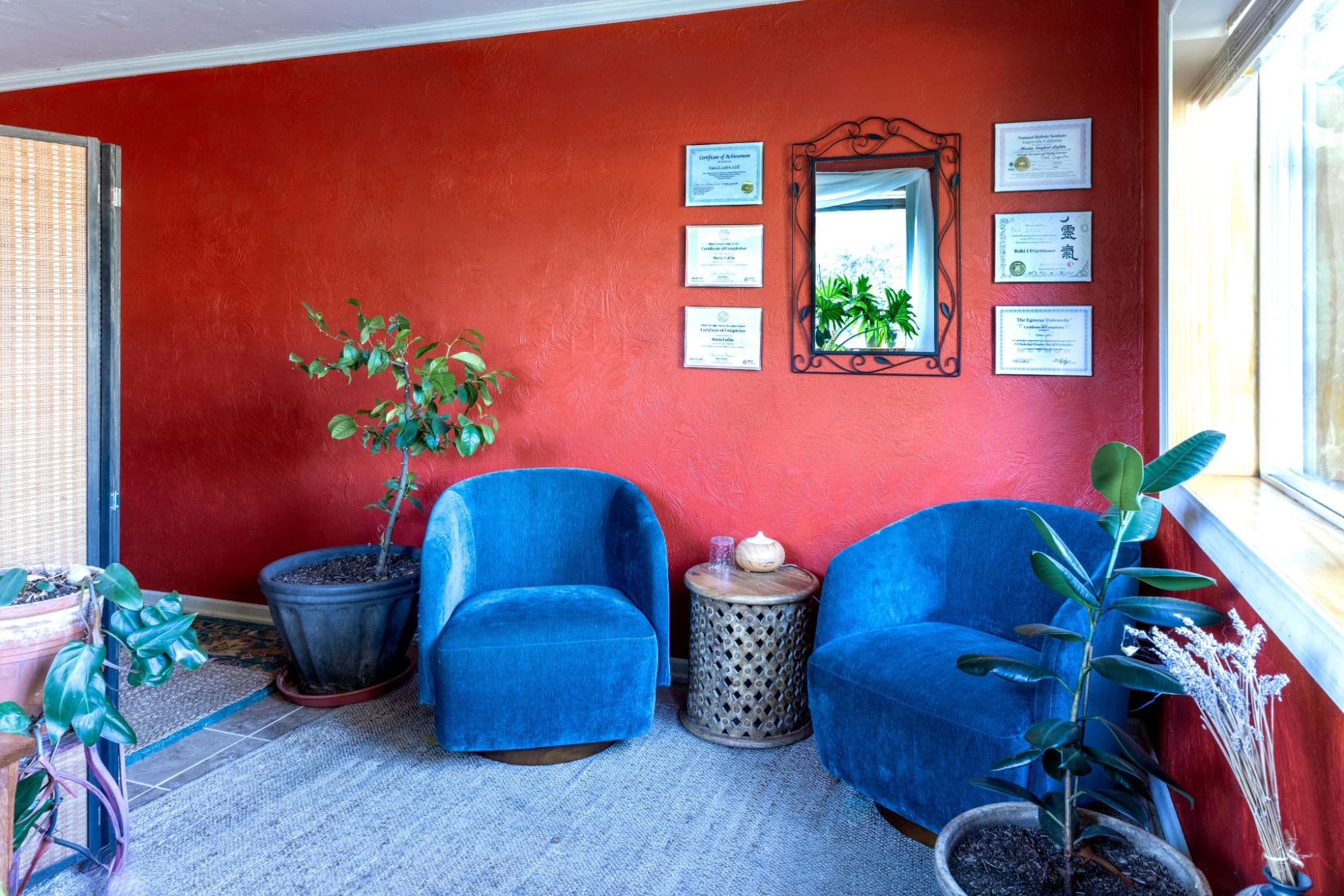 The waiting area at Body Harmony Massage, with two teal armchairs, houseplants and framed certificates